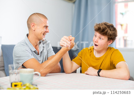 Son and his dad arm wrestling 114250683