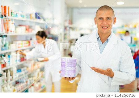 Male pharmacist offers medicine while standing in the trading floor of pharmacy Male pharmacist offers medicine while standing in the trading floor of pharmacy 114250716