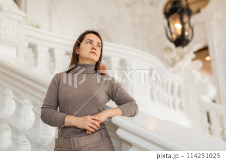Interested woman standing near stucco railings on stairs in antique palace Interested woman standing near stucco railings on stairs in antique palace 114251025