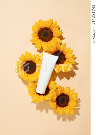 White tube without label for adding brand name or packaging, featured on sunflower texture over pastel pink flat form. Blank space for text with high angle view 114251742