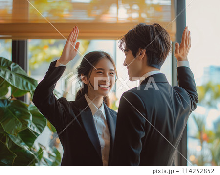 ハイタッチをして再会を喜び合う男女ビジネスパーソン 114252852
