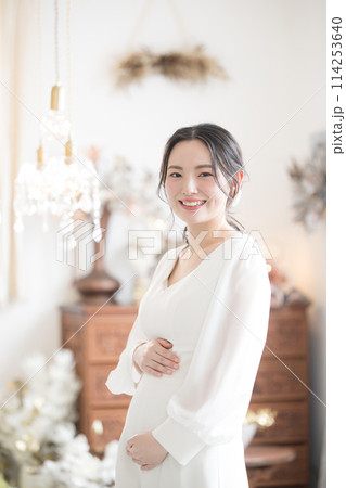 結婚式のマタニティフォトのイメージ　カメラ目線　前撮りや幸せいっぱいの妊婦さんのイメージ 縦 114253640