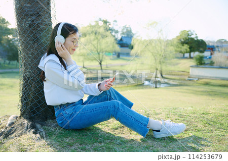 桜の下で音楽を聴く女性 114253679