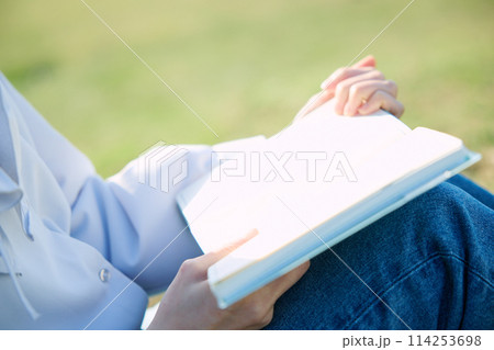 芝生の上で本を読む女性 114253698