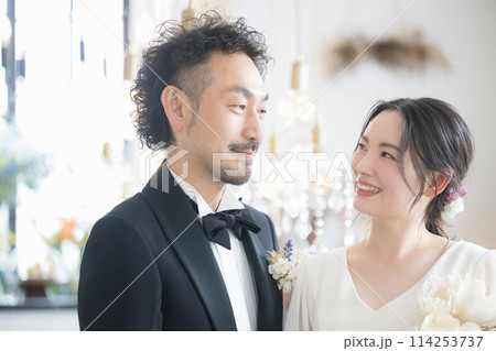 半逆光の美しい光で結婚式の花嫁と花婿の見つめ合うイメージ　前撮りやブライダル、ウェディングなどに 114253737