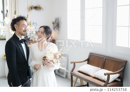半逆光の美しい光で結婚式の花嫁と花婿の見つめ合うイメージ　前撮りやブライダル、ウェディングなどに 114253738