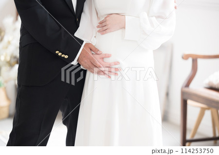 半逆光の美しい光で結婚式の妊婦の花嫁と花婿年の差カップル　マタニティフォトの前撮りやブライダル　顔無 114253750