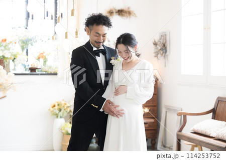 半逆光の美しい光で結婚式の妊婦の花嫁と花婿年の差カップル　マタニティフォトの前撮りやブライダル 114253752