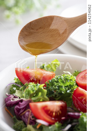 シンプルなグリーンサラダにオリーブオイルをかける 114254062