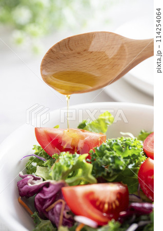 シンプルなグリーンサラダにオリーブオイルをかける 114254064