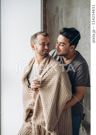 two handsome homosexual guys while standing near window two handsome homosexual guys while standing near window 114254631