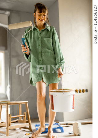 Portrait of a young woman painting walls at home Portrait of a young woman painting walls at home 114256127