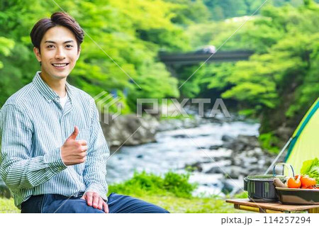 川原で一人キャンプする青年 114257294