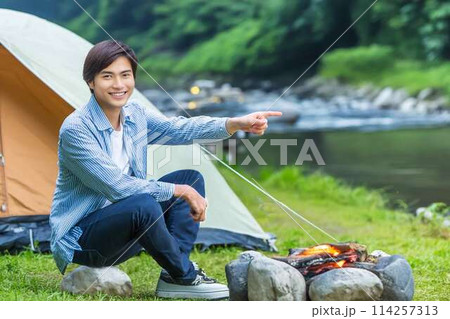 川原で一人キャンプする青年 114257313