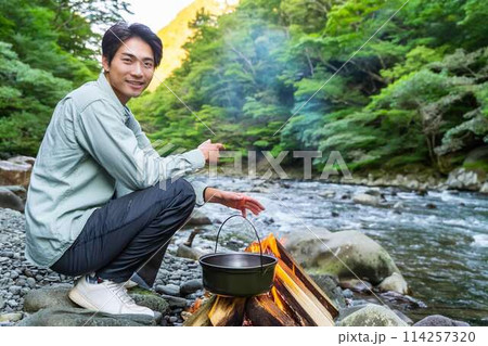 川原で一人キャンプする青年 114257320