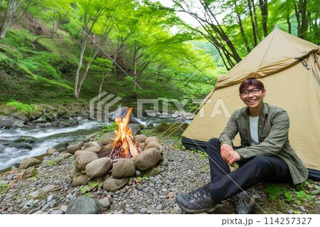 川原で一人キャンプする青年 114257327
