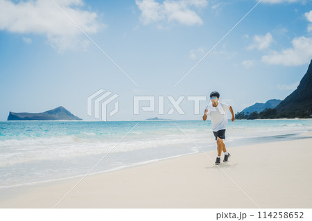 ハワイの砂浜でターコイズブルーの海沿いを走る若い男性 114258652
