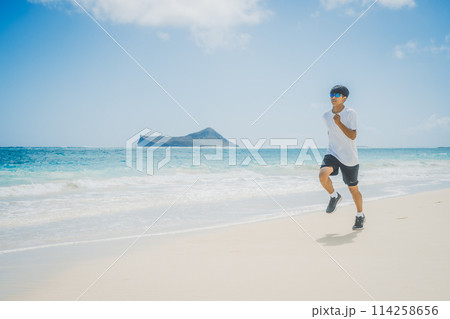 ハワイの砂浜でターコイズブルーの海沿いを走る若い男性 ハワイの砂浜でターコイズブルーの海沿いを走る若い男性 114258656
