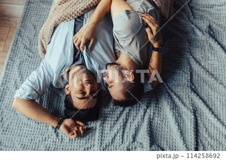 Handsome sleepy man with bristle kissing good night male partner lying in bed Handsome sleepy man with bristle kissing good night male partner lying in bed 114258692