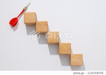 Five wooden cubes and red dart on white background Five wooden cubes and red dart on white background 114259476