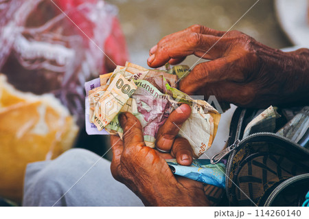 Older hands counting weathered paper Indonesian currency called Indonesian Rupiah, suggesting a transaction, economy and inflation Older hands counting weathered paper Indonesian currency called Indonesian Rupiah, suggesting a transaction, economy and inflation 114260140