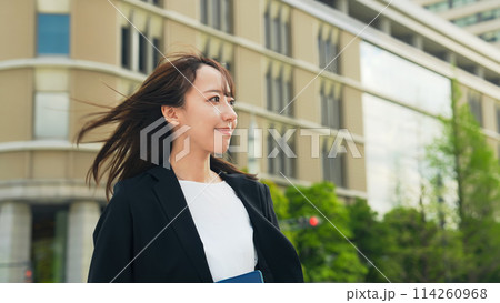 都市で風をきって歩く女性ビジネスパーソン 114260968