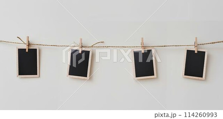 close up of a 4 blank note papers, photo frame on a rope with clothespins white background 114260993