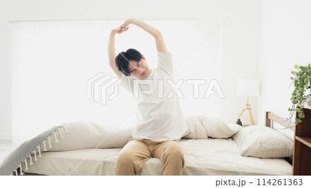 目覚めて伸びをする男性 114261363