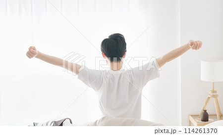 目覚めて伸びをする男性 114261370