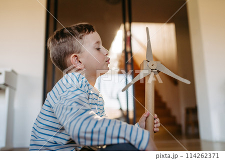 Boy holding wind turbine model. Concpet of renewable energy sustainable lifestyle for next generations. Boy holding wind turbine model. Concpet of renewable energy sustainable lifestyle for next generations. 114262371