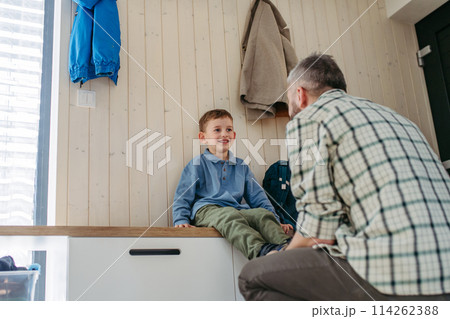 Father helping son get ready for kindergarten, preschool. Putting shoses on. Father helping son get ready for kindergarten, preschool. Putting shoses on. 114262388