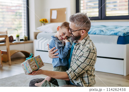 Dad get a handmade gift from little son, present wrapped in diy homemade wrapping paper. Happy Fathers day concept. Dad get a handmade gift from little son, present wrapped in diy homemade wrapping paper. Happy Fathers day concept. 114262438