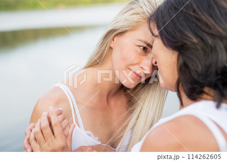 Adult daughter spending time with her mother outdoors. Beautiful daughter holding each other lovingly, hugging. Unconditional, deep maternal love, Mother's Day. Adult daughter spending time with her mother outdoors. Beautiful daughter holding each other lovingly, hugging. Unconditional, deep maternal love, Mother's Day. 114262605