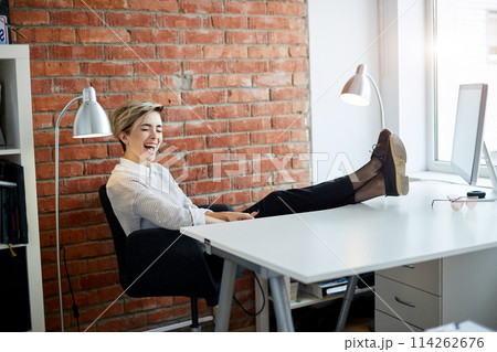 beautiful blond girl with legs on the table is singing thee sons at workplace 114262676