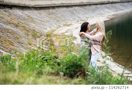 Adult daughter spending time with her mother. Mom and daughter outdoors, on walk by reservoir, lake embankment. Unconditional, deep maternal love, Mother's Day concept.. 114262714