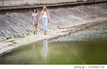 Adult daughter spending time with her mother. Mom and daughter outdoors, on walk by reservoir, lake embankment. Unconditional, deep maternal love, Mother's Day concept.. 114262718