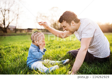 Father playing with little toddler boy in grass, having fun during warm spring day. Father's day concept. Father playing with little toddler boy in grass, having fun during warm spring day. Father's day concept. 114262929