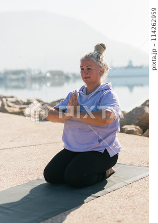 Mindful senior woman with dreadlocks meditating by the sea and beach - wellness and yoga practice Mindful senior woman with dreadlocks meditating by the sea and beach - wellness and yoga practice 114262959