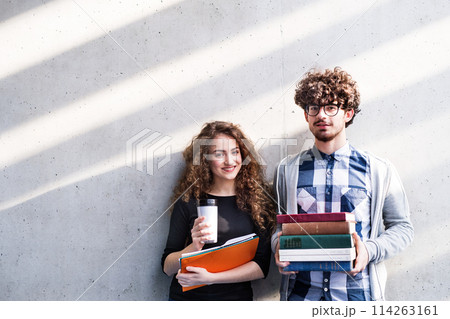 Young university students, holding stack of books, coffee, preparing for final exam. Study group. Young university students, holding stack of books, coffee, preparing for final exam. Study group. 114263161