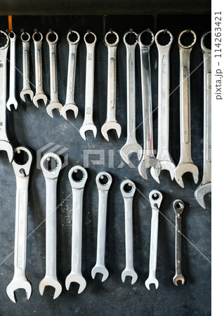 Combination wrenches set in auto repair shop. Mechanics repairing, maintaining car in garage. 114263421