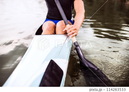 Close up of canoeist sitting in canoe holding paddle, in water. Concept of canoeing as dynamic and adventurous sport. 114263533