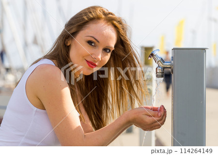 Woman drinking water from tap in marina. 114264149