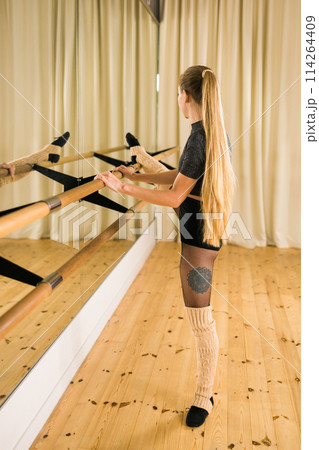 Young woman ballerina stretching and training at barre in dance studio - ballet and dancer concept Young woman ballerina stretching and training at barre in dance studio - ballet and dancer concept 114264409