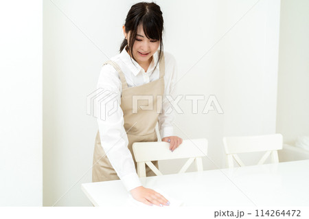 テーブルを拭くエプロンを着けた女性 114264472