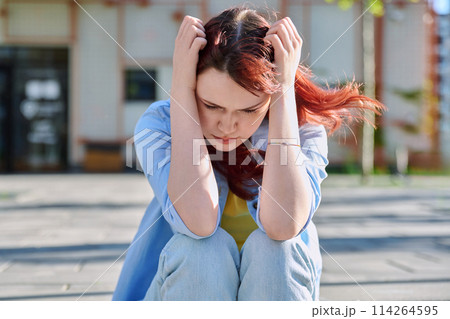 Upset sad unhappy young female sitting outdoor on steps Upset sad unhappy young female sitting outdoor on steps 114264595