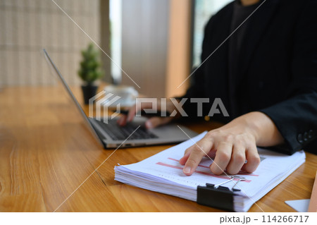 Businessman analyzing marketing data and using laptop on wooden table in office 114266717