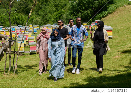 A diverse group of young friends and entrepreneurs explore small honey production businesses in the natural setting of the countryside. 114267313