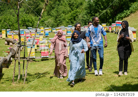 A diverse group of young friends and entrepreneurs explore small honey production businesses in the natural setting of the countryside. 114267319