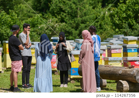A diverse group of young friends and entrepreneurs explore small honey production businesses in the natural setting of the countryside. 114267356
