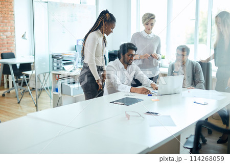 hindoo man is typing the necessary information while his co-workers watching him 114268059